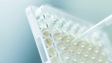 Scientist in a laboratory using a pipette to measure out a sample of clear liquid.png